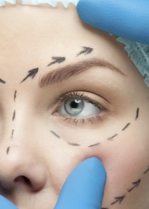 young woman with perforation lines on her face before plastic surgery operation. Beautician touching woman face.