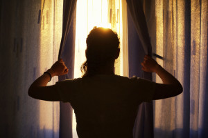 woman peaking out from behind curtains