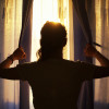 woman peaking out from behind curtains