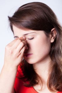 woman holding nose because of breathing problems