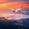 Passenger airplane. Landscape with big white airplane is flying in the sky over the clouds and sea at colorful sunset. Passenger aircraft is landing at dusk. Business trip. Commercial plane. Travel