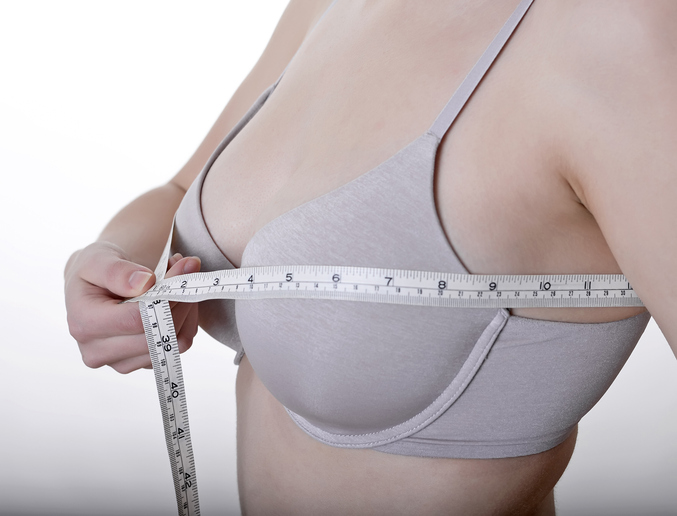 woman measuring breast after a having breast reduction surgery. 