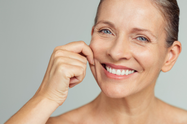 white woman demonstrating deep nasolabial folds on her face. 