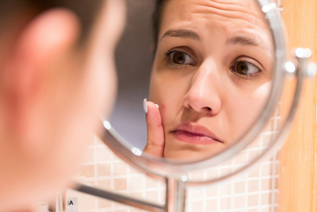 woman looking at her nose with dissatisfaction